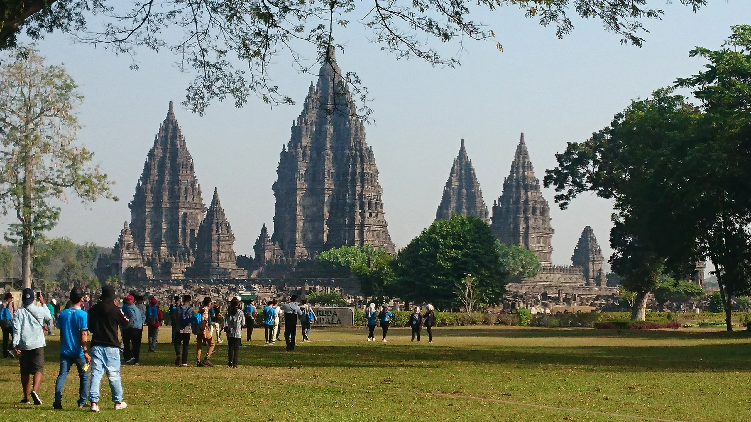 Prambanan Temple near Yogyakarta, Indonesia, with visitors walking across the grounds in front of the historic temple complex.